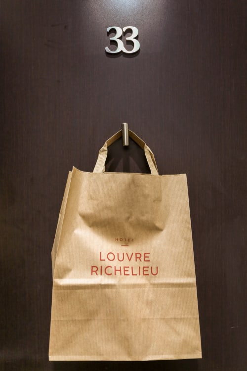 Sac en papier de l'Hôtel Louvre Richelieu accroché à la porte numéro 33 à Paris