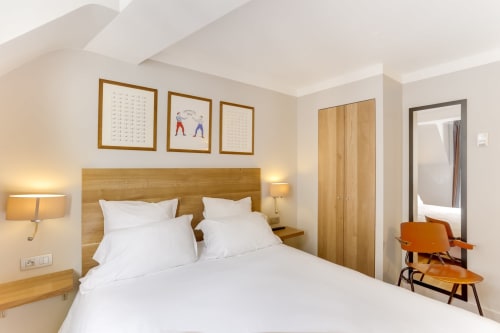 Chambre moderne de l'Hôtel Louvre Richelieu à Paris avec lit en bois, draps blancs et mobilier contemporain
