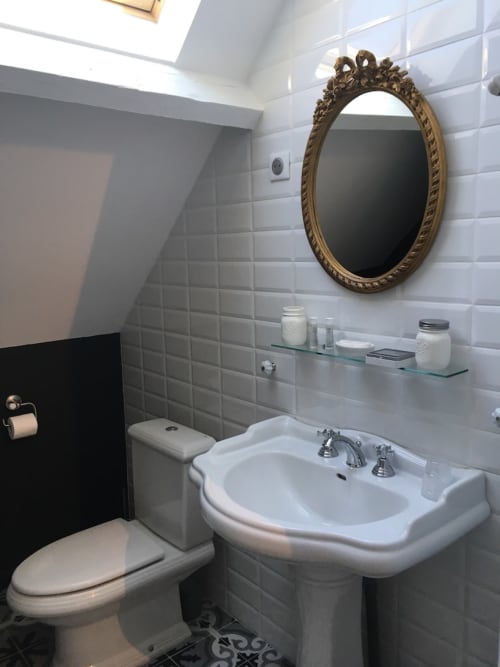 Elegant bathroom at Le château d'Hermonville with pedestal sink, ornate gold mirror, and subway tile walls