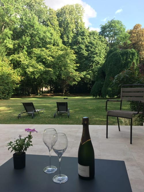 Champagne bottle and glasses on terrace overlooking gardens at Le château d'Hermonville, Hermonville