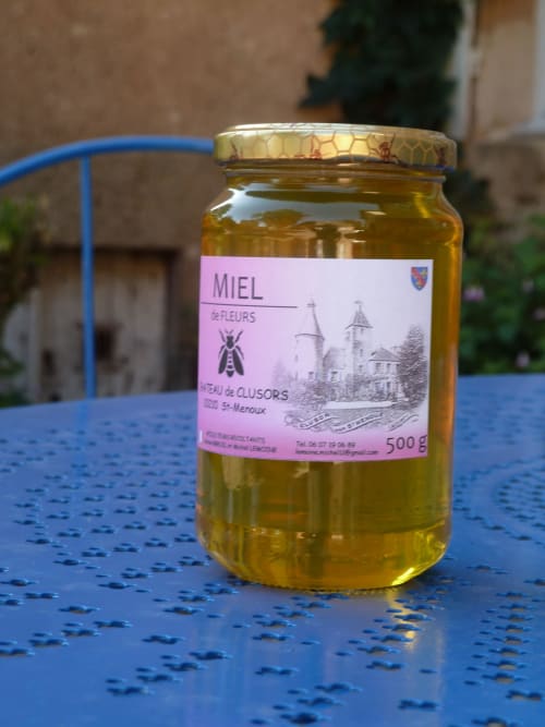 Jar of honey from Château De Clusors in Saint-Menoux, France on blue table