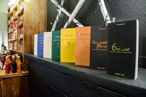 Colorés livres de cuisine français exposés sur une étagère sombre à l'hôtel Les Filles du Bord de Mer à Port-en-Bessin
