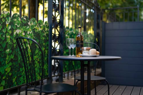 Élégante terrasse extérieure à Un Air De Famille à Vittel avec bouteille de vin, verres et amuse-bouches sur une table ronde noire