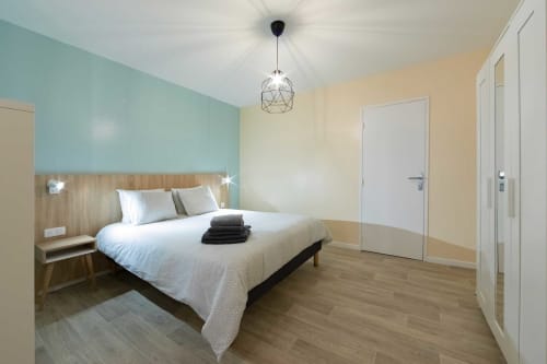 Chambre moderne de l'appartement Valériane à Un Air De Famille, Vittel, avec mur d'accent turquoise et mobilier en bois