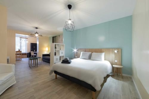 Chambre moderne de l'appartement Valériane à Un Air De Famille, Vittel avec mur d'accent turquoise, lit blanc et suspension géométrique