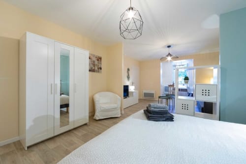 Appartement Valériane à Un Air De Famille à Vittel avec armoire blanche, lit, coin salon et espace cuisine-salle à manger