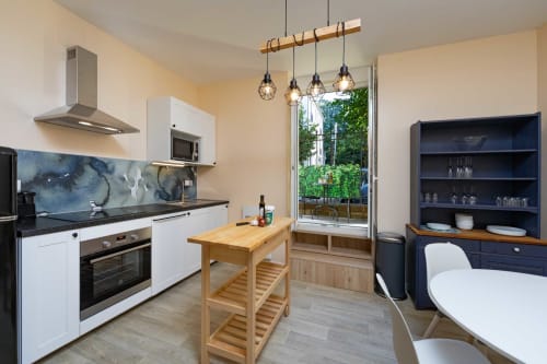 Cuisine moderne et coin repas de l'appartement Valériane au gîte Un Air De Famille à Vittel avec îlot en bois et balcon