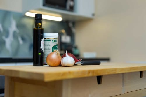 Comptoir de cuisine à Un Air De Famille avec huile d'olive, ail, oignon et ingrédients gourmets dans l'appartement de Vittel
