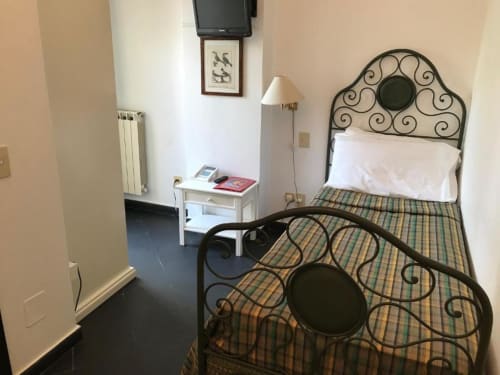 Einzelzimmer des Hotel Beau Rivage in Alassio mit Schmiedeeisenbett, Fernseher, Nachttisch und Radiatorheizung