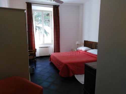 Zimmer des Hotel Beau Rivage mit roter Bettwäsche, Meerblick, dunklem Bodenbelag und großem Spiegel in Alassio, Italien