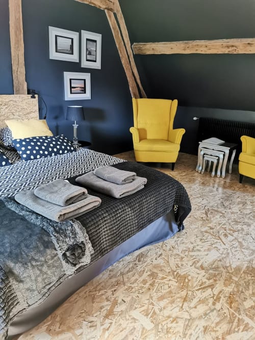 Chambre avec fauteuil jaune, literie à motifs et serviettes à La Cour d'Hortense B&B à Sailly-Flibeaucourt, France