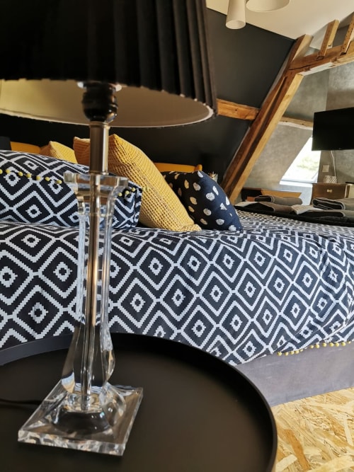 Coin salon confortable à La Cour d'Hortense B&B avec coussins à motifs, lampe de table et mobilier en bois