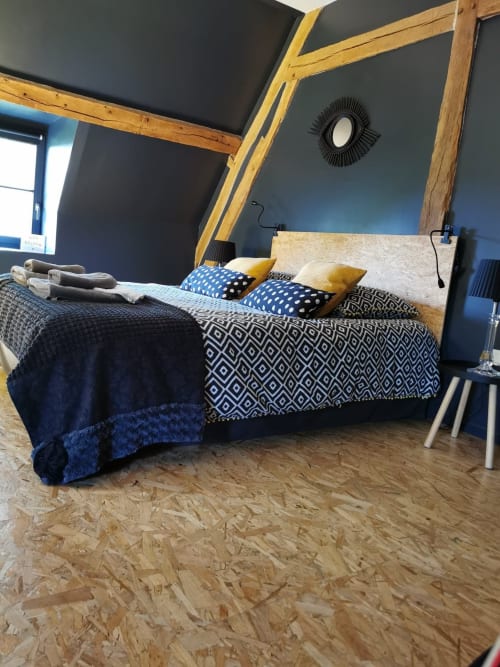 Chambre contemporaine à La Cour d'Hortense avec murs bleus, poutres en bois, literie motifs et sol en liège