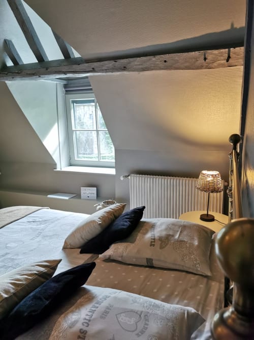 Chambre mansardée lumineuse à La Cour d'Hortense avec plafond incliné, fenêtre de toit, radiateur, lampe en osier et décoration