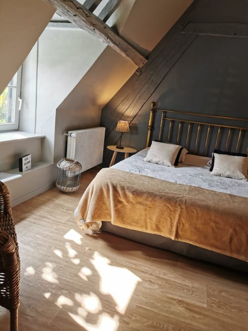 Chambre cosy sous les toits à La Cour d'Hortense avec lit en laiton, poutres bois et lumière du jardin