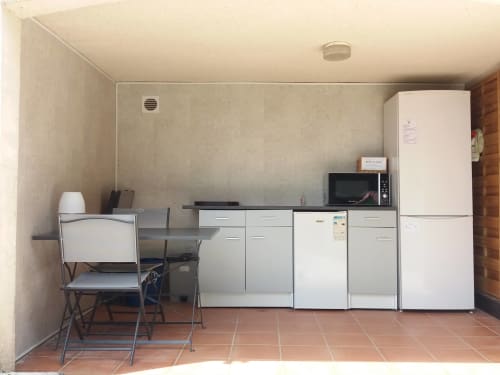 Compact kitchenette with white refrigerator, microwave, and stovetop in Belloréade glamping refuge, Belloc