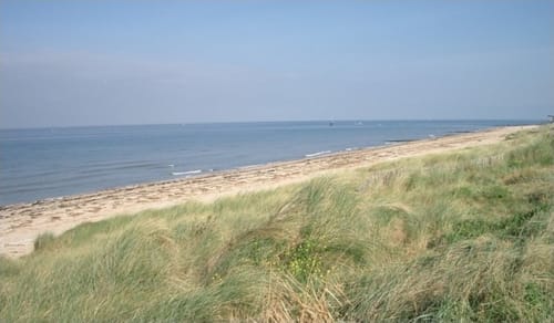 Vista de la playa costera en el hotel Les Cabines en Houlgate, Francia con arena y vegetación de dunas