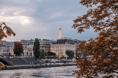 La Tour Eiffel et les toits de Paris vus depuis la Seine près de l'Hôtel Louvre Richelieu, feuillages d'automne encadrant la scène