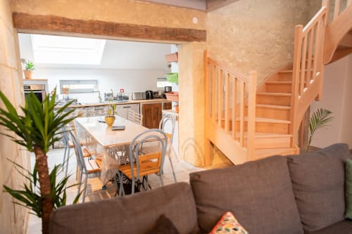 Espace de vie ouvert au Gîte Wat, Les gîtes des châteaux, avec table à manger, canapé marron, escalier en bois et design moderne