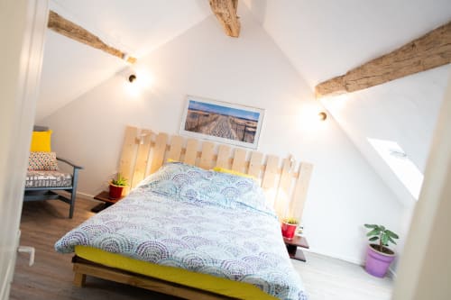 Chambre lumineuse aux Gîtes des Châteaux avec poutres apparentes, lit jaune, parure motifs et décor rustique