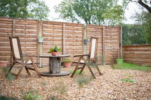 Espace de détente en terrasse aux gîtes des châteaux à Vallières-les-Grandes avec chaises en bois, table et plantes en pots