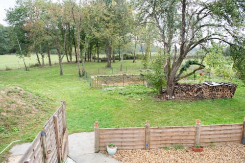 Clôture rustique en bois et patio en gravier surplombant une pelouse soignée avec arbres matures aux gîtes des châteaux,