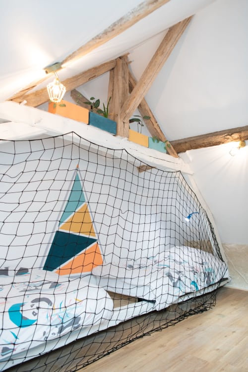 Chambre de jeux douillette sous les combles avec décor géométrique et filet de pêche aux Gîtes des Châteaux