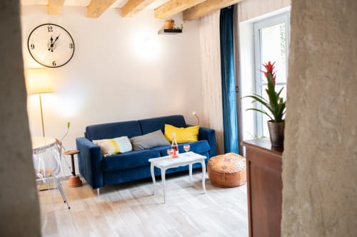 Séjour lumineux et contemporain du gîte Les châteaux avec canapé bleu marine, table basse blanche et grande fenêtre donnant sur