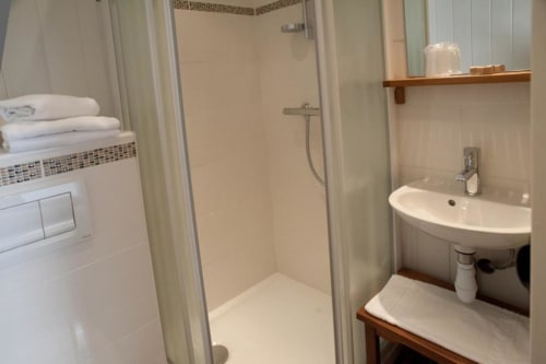 Modern bathroom at Hôtel Maison Richet with shower, curved sink, and white towels in Les Sables-d'Olonne