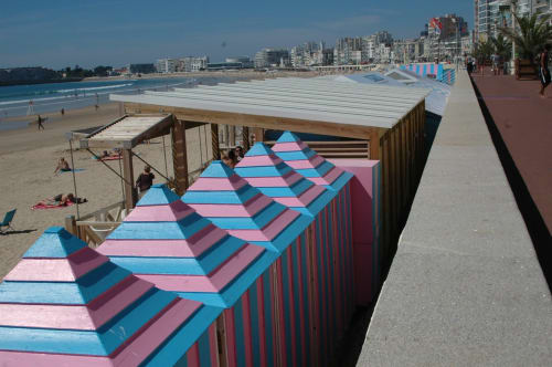 Colorful striped beach cabins at Les Sables-d'Olonne beachfront promenade with ocean and coastal buildings