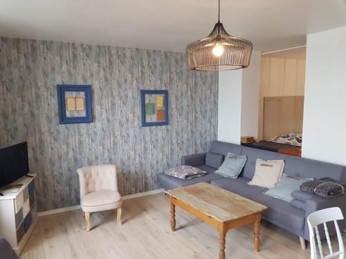 Salon de charme moderne à Vue D'ici à Saint-Valery-sur-Somme avec canapé gris, table en bois et vue sur mer