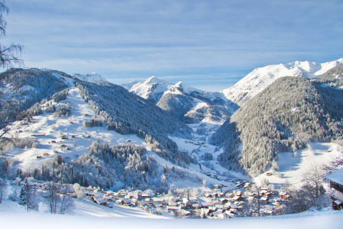 Vallée alpine enneigée avec chalets traditionnels et montagnes forestières, Queige France