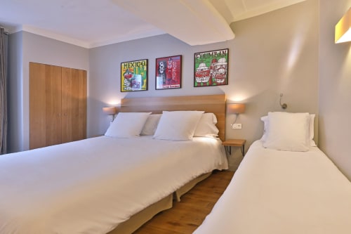 Chambre d'hôtel à l'Hôtel Louvre Richelieu Paris avec lit double, lit simple, mobilier en bois et œuvres d'art mexicaines colorées
