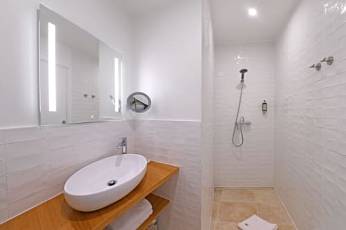 Salle de bain moderne à l'Hôtel Louvre Richelieu Paris avec vasque, miroir rétroéclairé et douche spacieuse