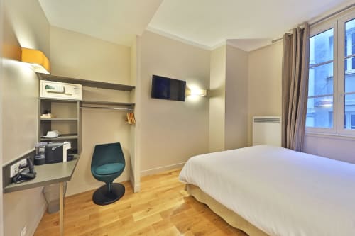 Chambre double confort de l'Hôtel Louvre Richelieu Paris avec lit, bureau, TV, parquet et équipements modernes