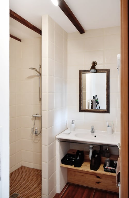 Salle de bain moderne avec douche à l'italienne, vasque, meuble de rangement en bois et miroir encadré au Logis De La Bénétière