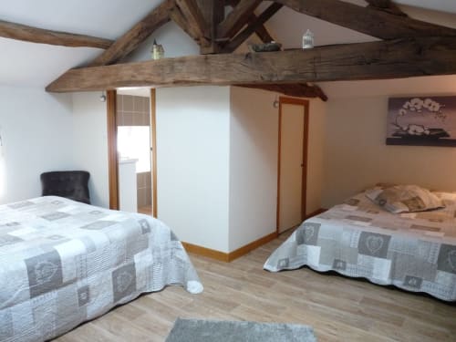 Rustic bedroom with exposed beams at Logis De La Bénétière in Treize-Vents, featuring two beds and garden view