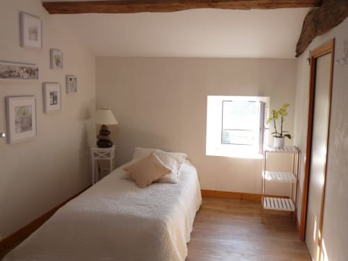 Bright bedroom at Logis De La Bénétière with single bed, wooden beams, framed artwork, and garden view window in Treize-Vents