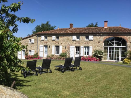 Logis De La Bénétière B&B in Treize-Vents features stone façade, loungers on manicured lawn, pink flowers