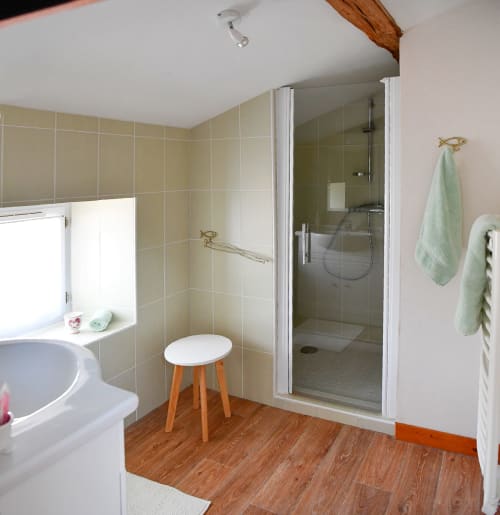 Modern bathroom at Logis De La Bénétière with walk-in shower, beige tiles, wooden flooring, and sweet towels