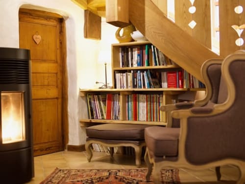 Coin lecture douillet avec étagères en bois, cheminée et fauteuils à La Bageatière B&B à Lépin-le-Lac