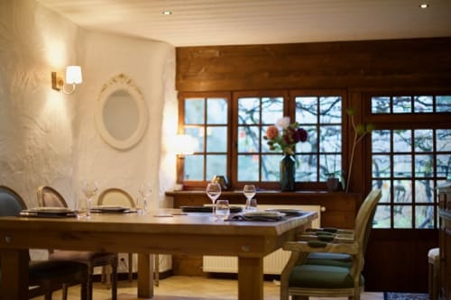 Élégante salle à manger de la Chambre d'hôtes La Bageatière à Lépin-le-Lac avec table en bois, cheminée et vue sur le lac par les grandes fenêtres
