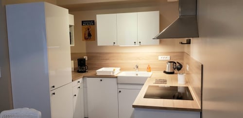 Cuisine moderne de l'appartement La Vie en Rose à La Maison Virginie, Montargis, avec armoires blanches et plan de travail en bois