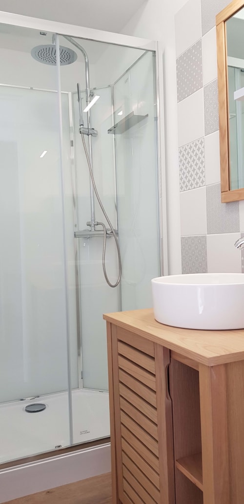 Salle de bain moderne avec douche pluie, meuble vasque en bois et lavabo blanc à La Maison Virginie B&B à Montargis