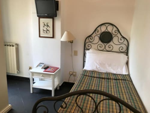 Gemütliches Hotelzimmer im Hotel Beau Rivage in Alassio mit verziertem Bett, weißem Nachttisch, Stehlampe und Wand-TV