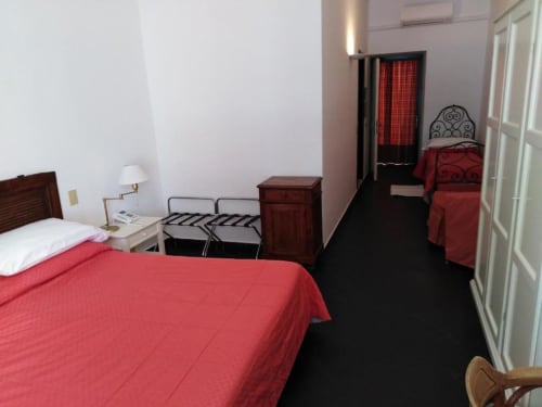 Hotelzimmer des Beau Rivage in Alassio mit roter Bettwäsche, dunklem Boden und klassischen Möbeln