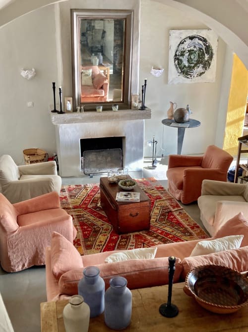 Élégant séjour du gîte Saint Martin à Ollioules avec cheminée, fauteuils roses et tapis rouge à motifs
