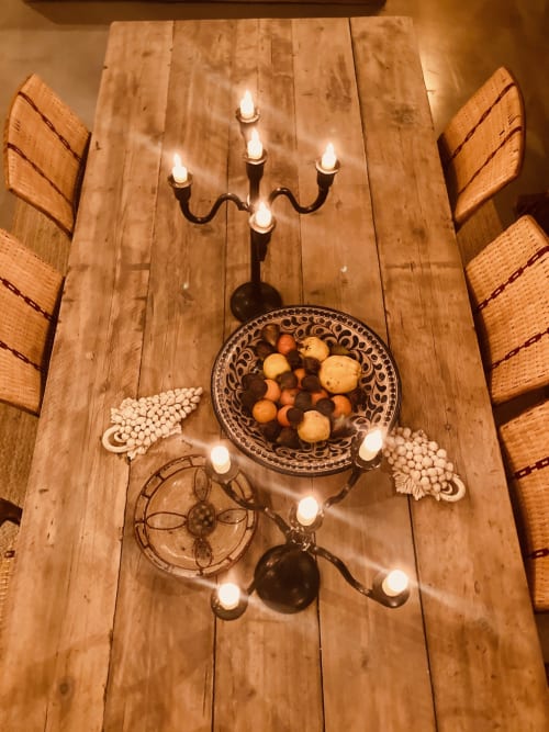 Rustic wooden dining table at Saint Martin B&B with candelabra, decorative bowl of fruits, and ambient candlelight