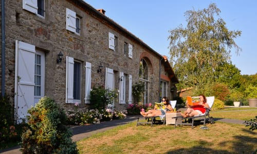Guests relaxing in deck chairs at Logis De La Bénétière B&B in Treize-Vents, with stone cottage and gardens