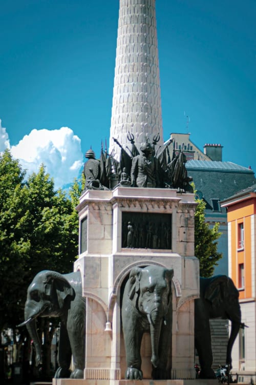 Bronze elephant statues supporting ornate monument with white tower in Lépin-le-Lac